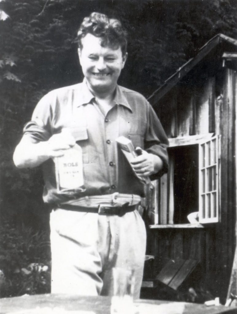 Malcolm Lowry with two of his best friends, a bottle and a book