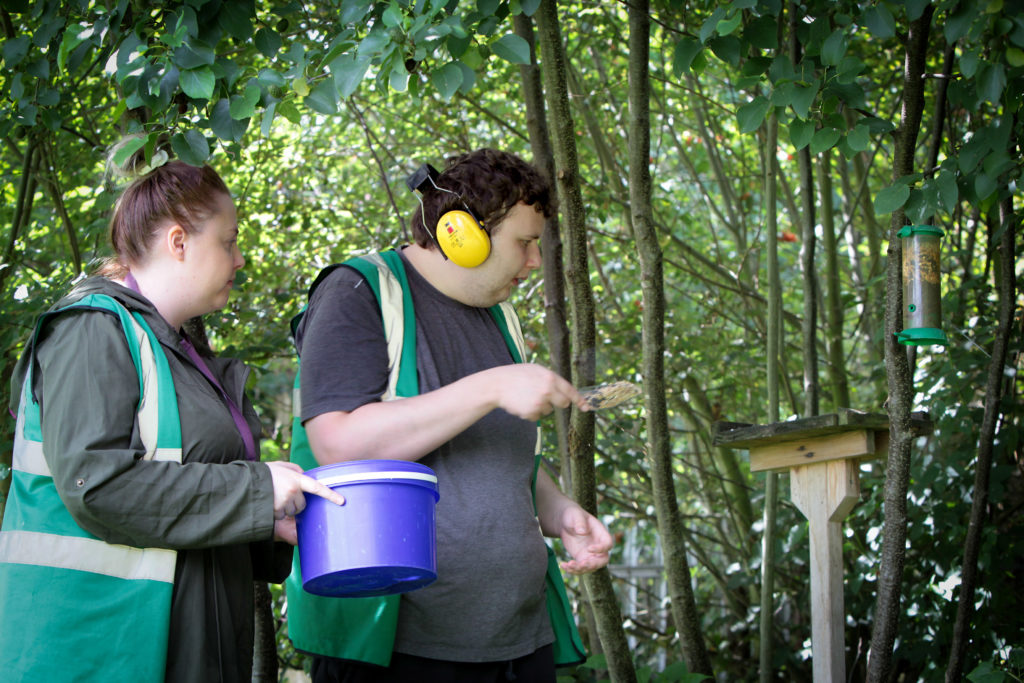 Service user Rhys Gillam feeds the birds with support worker Jasmine Formstone from Autism Together.